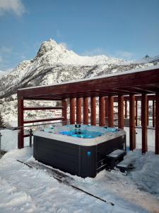 bañera de hidromasaje en una terraza con una montaña cubierta de nieve en Seaview and private roof top terrace with jacuzzi in Lofoten, en Svolvær