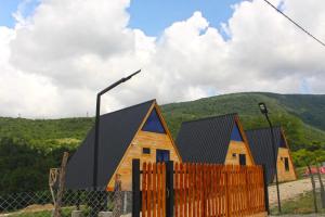 a row of houses with a fence and mountains in the background at Le GaBe Canyon Eco Houses in Martvili