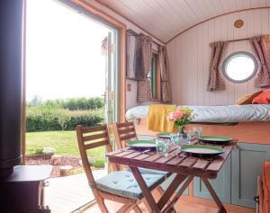 a table and chairs in a room with a bed at Luxury Shepherds Hut in Stonehouse