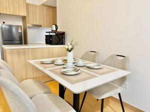 a white table with chairs and a white vase with flowers at Gamuda Cove,Splash Mania by Solace Place in Pulau Kempas