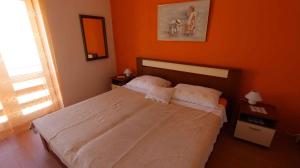 a bedroom with a white bed with an orange wall at One-Bedroom Apartment Malinska near Sea 2 in Malinska