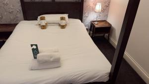 two teddy bears sitting on a bed with towels at Regency Hotel in Leicester