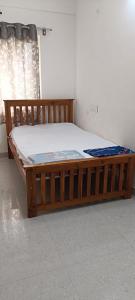 uma cama de madeira num quarto com uma janela em LetsGokarna vacation stay em Gokarna