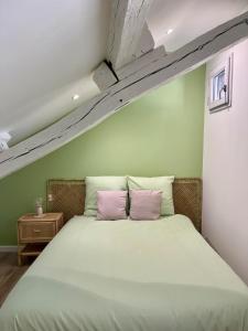 1 cama con 2 almohadas rosas en una habitación en La Rose de Vert, en Rouen
