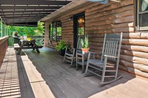 a wooden deck with two chairs and a table at WaterFront Cabin Hot Tub Kayaks Firepit Game Consoles in Tunkhannock