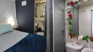 ein Schlafzimmer mit einem Bett und ein Badezimmer mit Blumen in der Unterkunft Renacer NATURAL GETAWAY MOVISTAR ARENA in Bogotá