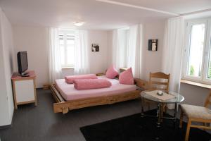 Un dormitorio con una cama con almohadas rosas y una mesa. en Hirschen B&B, en Maienfeld