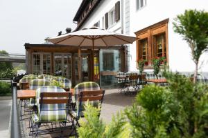 un patio al aire libre con mesas, sillas y una sombrilla en Hirschen B&B en Maienfeld