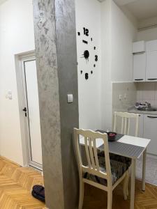una cucina con tavolo, sedie e orologio sul muro di Loli apartman a Kraljevo