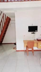 a room with a desk with a television and a staircase at Penginapan & Homestay Ratu Pantai Geopark Ciletuh in Cikadal