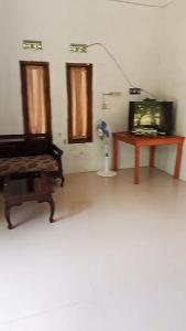 a living room with a bed and a desk with a television at Penginapan & Homestay Ratu Pantai Geopark Ciletuh in Cikadal