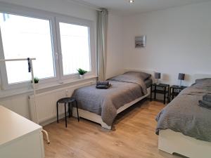 a bedroom with two beds and two windows at TeamStay Apartments & Boardinghouses in Hellstein