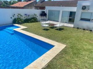 a backyard with a blue swimming pool and grass at LOS SAUCES CHASCOMUS in Chascomús