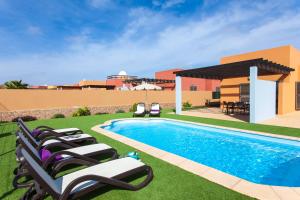 a pool with lounge chairs next to a house at Villa con Piscina ,Vista Mar y campo de golf in Caleta De Fuste