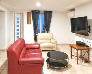 a living room with a red couch and a television at Maison charmante à Crouy-sur-Ourcq avec jardin privé. in Mary-sur-Marne