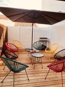 a group of chairs and tables with an umbrella at Maison rénovée à 300m de la mer in Saint-Hilaire-de-Riez
