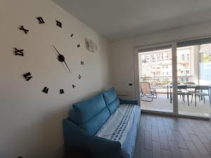 a living room with a blue couch and a clock on the wall at laperlablu in Alassio
