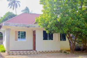 a small white house with a tree in front of it at The Best Travelling Zanzibar Apartment in Zanzibar City