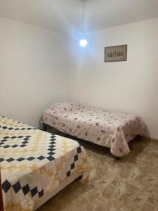 Zimmer mit 2 Betten und einem Bild an der Wand in der Unterkunft Departamento cerca a Cerro Azul in Hualcará