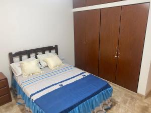 ein Schlafzimmer mit einem Bett und einem Holzschrank in der Unterkunft Departamento cerca a Cerro Azul in Hualcará