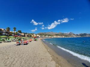 a group of people sitting on a beach at c'est la vie giardini in Giardini Naxos