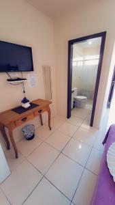 a living room with a television and a table and a toilet at Pousada Parque Central in Penha