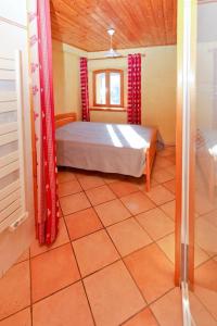 a bedroom with a bed with red curtains and a tiled floor at Le Chalet des Séraphins in Saint-Sorlin-dʼArves