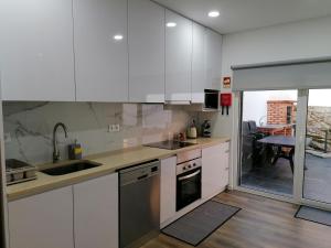 a kitchen with white cabinets and a sink at Refúgio Vale da Pipa in Figueiró dos Vinhos