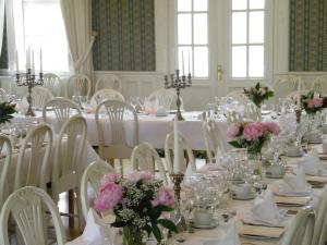 a white room with a long table with pink flowers at Sjöbo Gästgifvaregård in Sjöbo