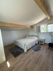 a bedroom with a white bed and a wooden floor at Location vacances - parking inclus in Puget-sur Argens