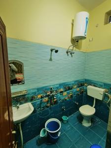 a blue tiled bathroom with a toilet and a sink at Shri Ganesh Homestay in Prayagraj
