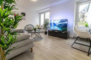 Una sala de estar con un sofá y un televisor de pantalla plana. en FeWoMo Stilvolles EG Appartment, Brauneberg, 4 Pers, Boots Slipanlage, Moselradweg, Seniorengerecht, en Brauneberg