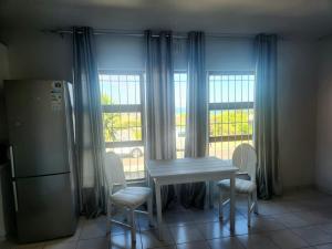 a kitchen with a table and chairs and windows at Horizon Gastehuis in Saldanha
