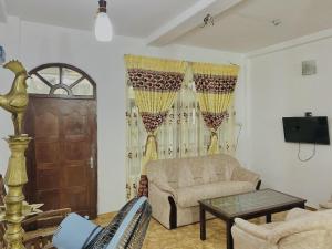 a living room with a couch and a table and a door at Fantasia Residence in Wattala