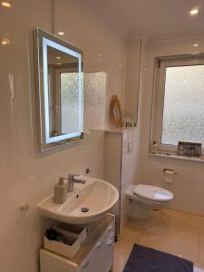 un bagno con lavandino, WC e specchio di Ferienwohnung im Stadtzentrum Wilhelmshaven a Wilhelmshaven Altre 9 foto