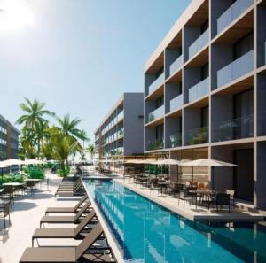 a resort pool with lounge chairs and umbrellas at Flat Recanto Muro Alto - Porto de Galinhas in Ipojuca