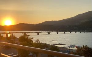 a bridge over a river with the sunset in the background at La terrasse au bord du Lac, vue panoramique lac et montagnes , 2 ch, linge et ménage inclus in Savines +32 photos