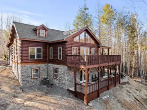 a large wooden house with a deck in the woods at Woodlake Log Cabin in Elk Park