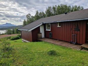 a red house with a wooden deck in the grass at Cabin with lovely view in Lakså