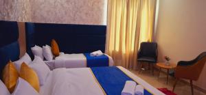 a hotel room with two beds and two chairs at BlueNeck Ayodhya-Near ShriRam Mandir in Ayodhya