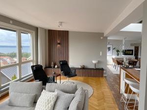 a living room with a couch and chairs and a kitchen at Villa med utsikt, centralt, nära Elmia in Huskvarna