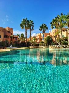 a large swimming pool with palm trees and buildings at Apartamento ideal a un paso de la playa in Playas de Vera