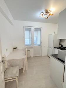 a white kitchen with a table and a refrigerator at Жилой комплекс Гулдер 72 in Almaty +13 photos