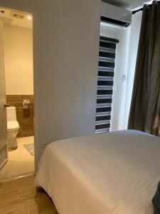 a bedroom with a white bed and a bathroom at Convenient Davao Getaway in Davao City