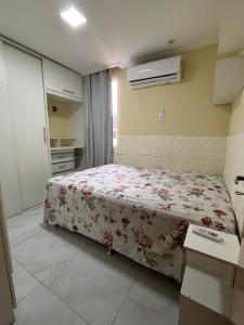 a bedroom with a bed with a floral bedspread at Aconchego em Campo Grande - Guaratiba in Rio de Janeiro