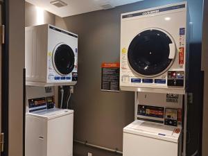 a laundry room with two washing machines and a washer at APA Hotel Higashi Shinjuku Kabukicho in Tokyo