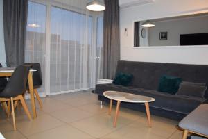 una sala de estar con un sofá y una mesa en Apartament w Niechorzu przy latarni z garażem, en Niechorze
