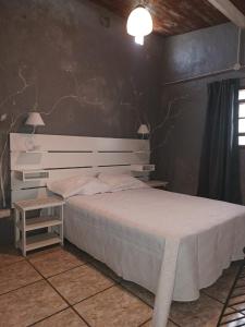a bedroom with a white bed and a table at La casita en San Miguel del Monte in San Miguel del Monte