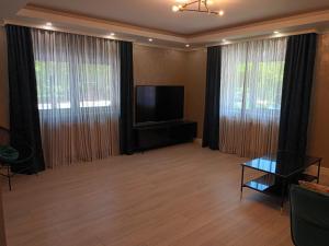 a living room with a flat screen tv and windows at ClausStudio Greenfield Baneasa Therme Aeroport in Otopenii de Jos