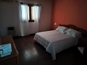a bedroom with a white bed and a window at La casita Libertad en San Miguel del Monte in San Miguel del Monte